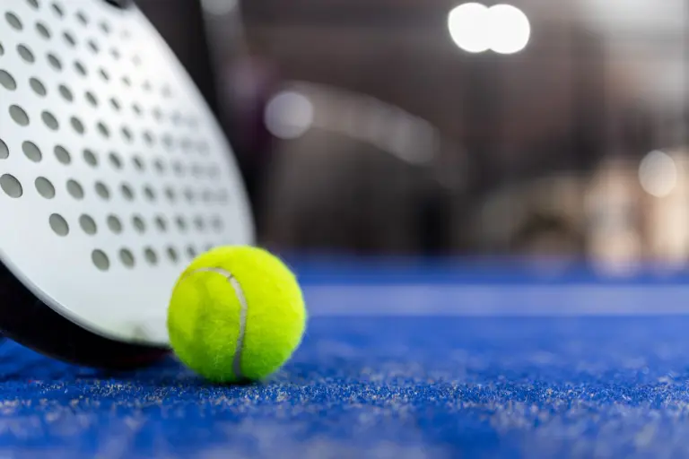 Racchetta e palla da padel su campo blu
